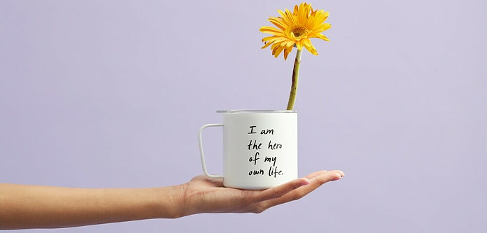 hand holding out a mug that says