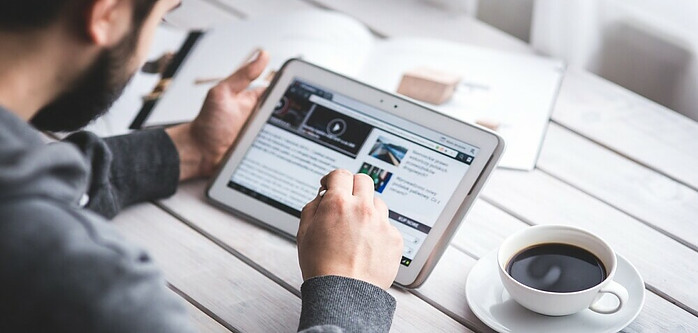 a person reading a blog with a cup of coffee