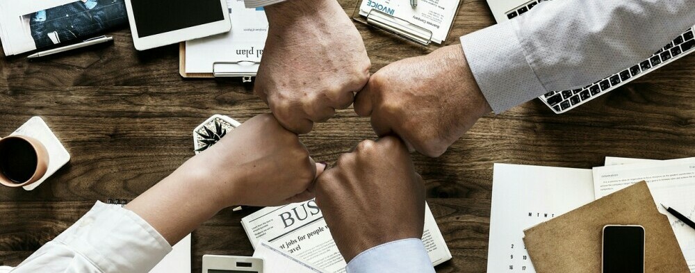a group of 4 people bumping fists to show their support for one another