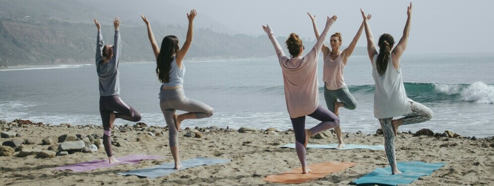 a group of women doing yoga on the beach for self improvement