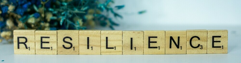 resilience written in scrabble letters sitting in front of flowers