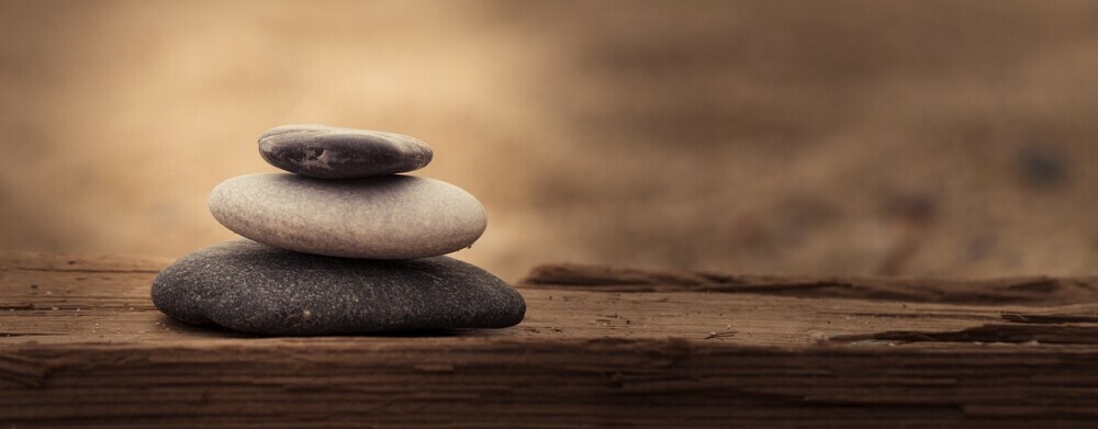 stones neatly stacked on a board by the water 